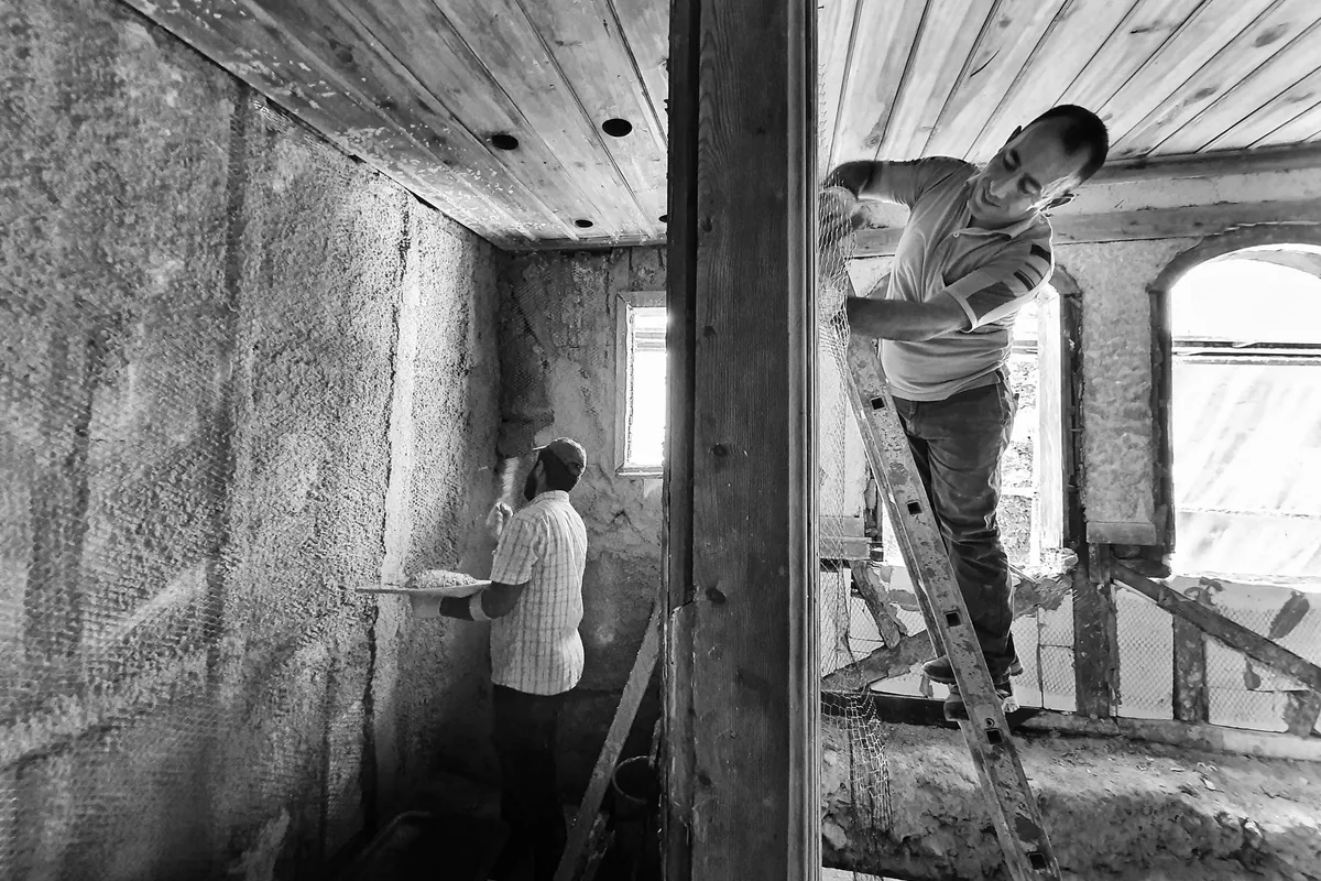 Artisans intervenant sur les parois d'un intérieur ancien